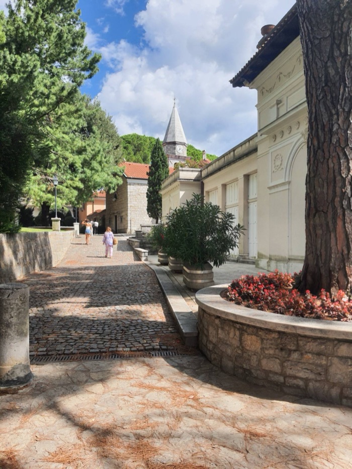 Gepflasterter Weg zwischen alten Häusern, im Hintergrund ein Kirchturm